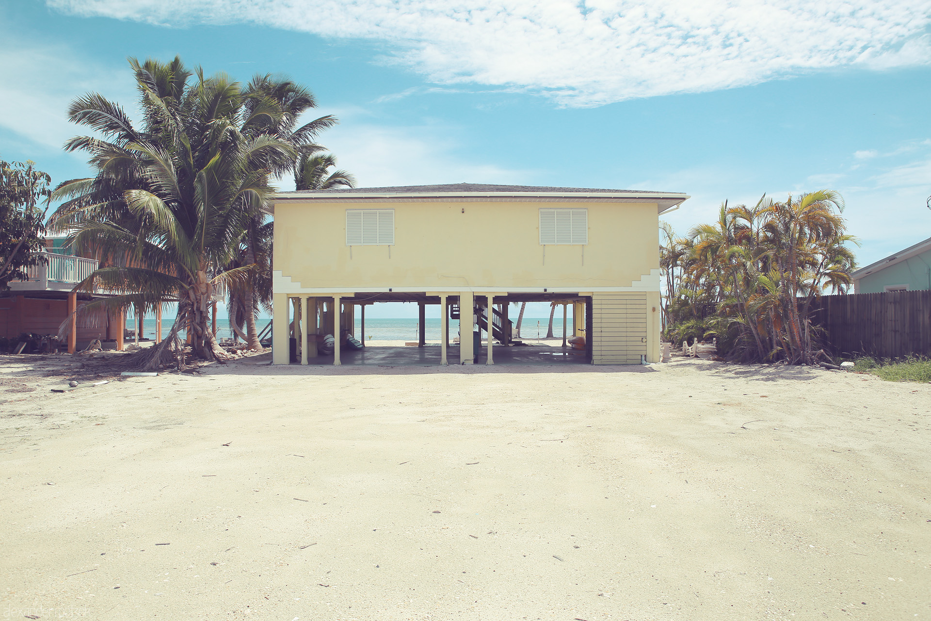 Foto von A quaint stilt house stands before azure waves and swaying palms in Monroe County, Florida, epitomizing tranquil coastal living.