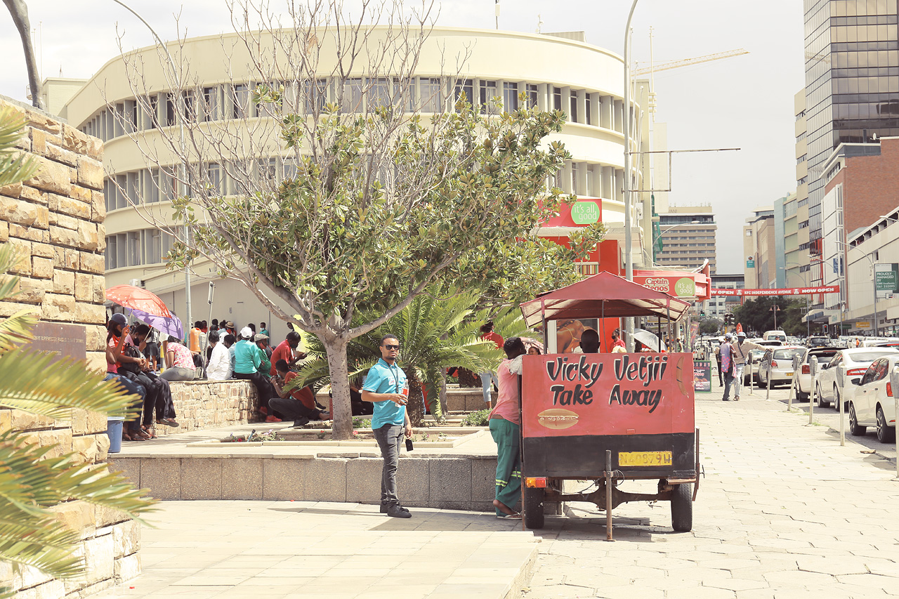 Foto von A bustling Windhoek scene with locals by a street food cart, capturing the city's vibrant everyday life.