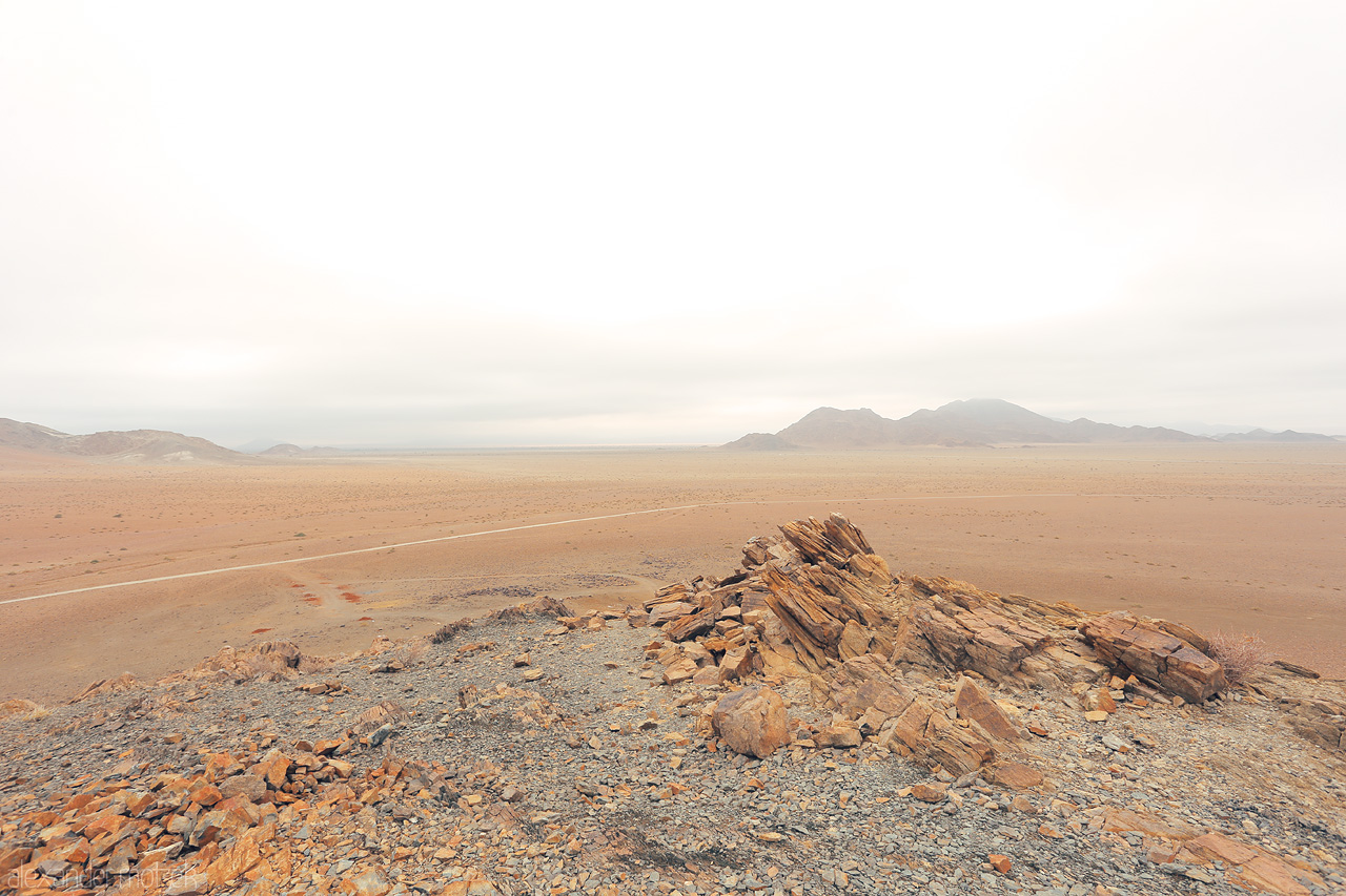 Foto von A vision of Hardap: solitary rocks guard vast, quiet Namibian expanse under soft, hazy skies.