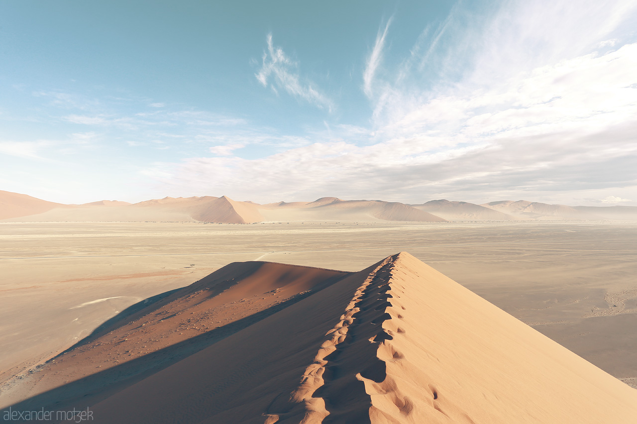 Foto von Vastness of Sossusvlei - textured dunes juxtapose serene skies in Namibia's desert scape.