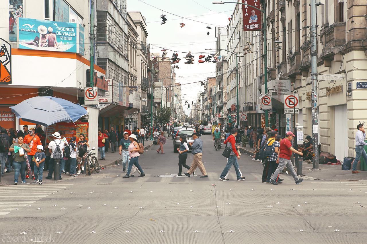 Zapatos Capitalino Foto von Pedestrians cross a bustling street in Cuauhtémoc, with shoes overhead hinting at local urban tales.