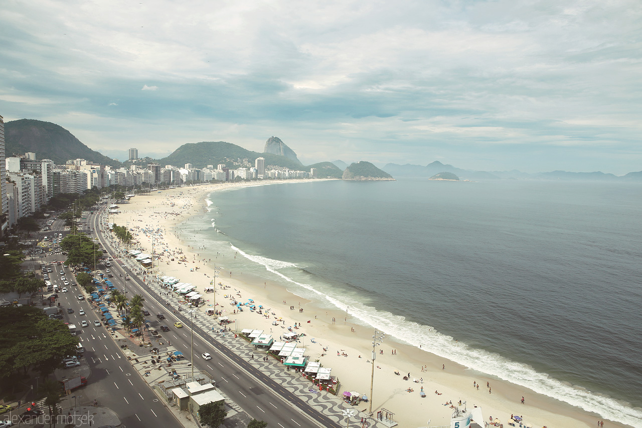 Foto von Copacabana Beach stretches beneath a cloudy sky in Rio de Janeiro, where urban life meets pristine sands and ocean waves.