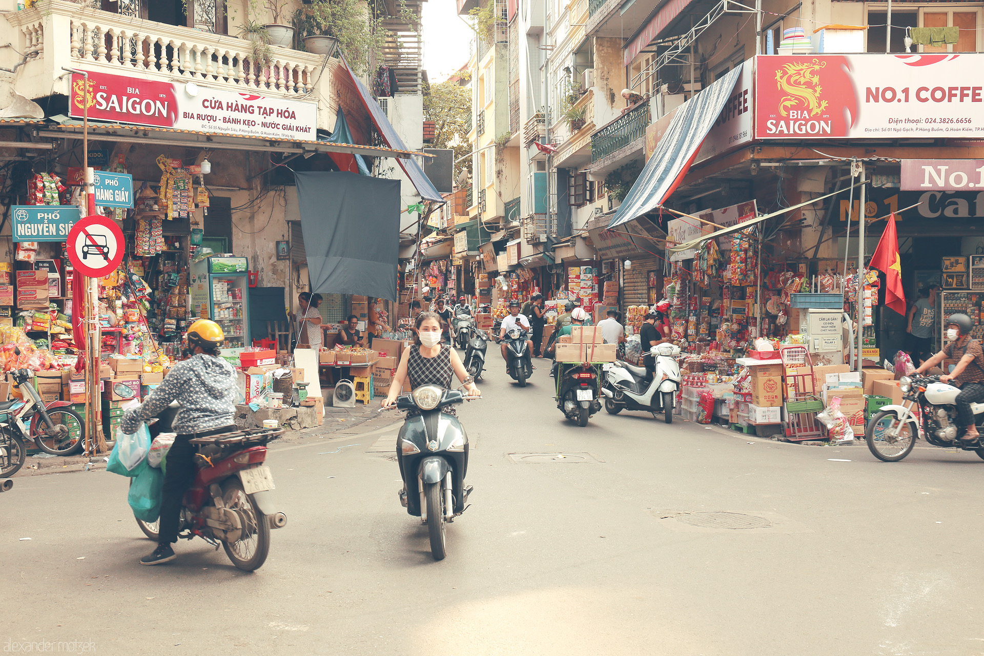 Foto von Scooters weave between vibrant street stalls in Phuong Hàng Buom, Hanoi, alive with color, commerce, and the energy of daily city life.