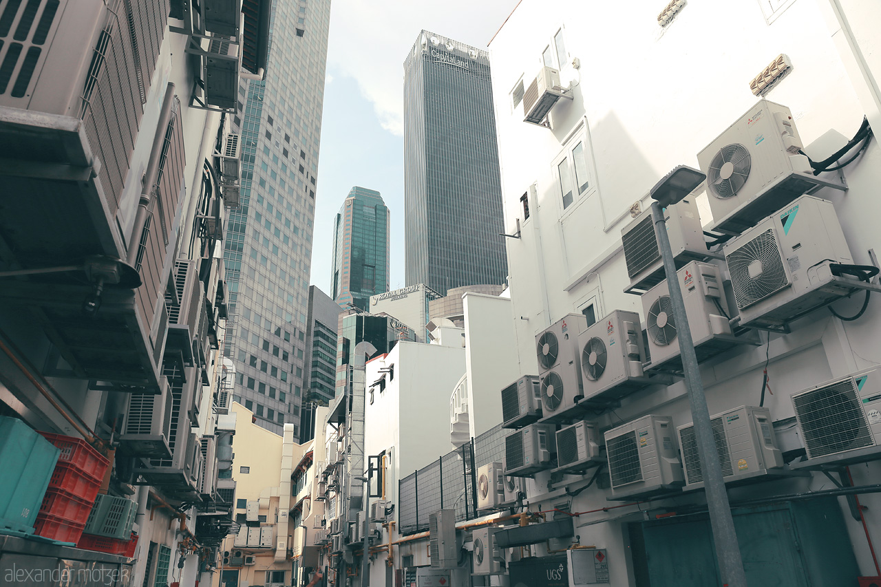 Foto von A juxtaposition of modern skyscrapers and old buildings with air conditioners in a back alley of Singapore, revealing the city's unique blend of old and new.