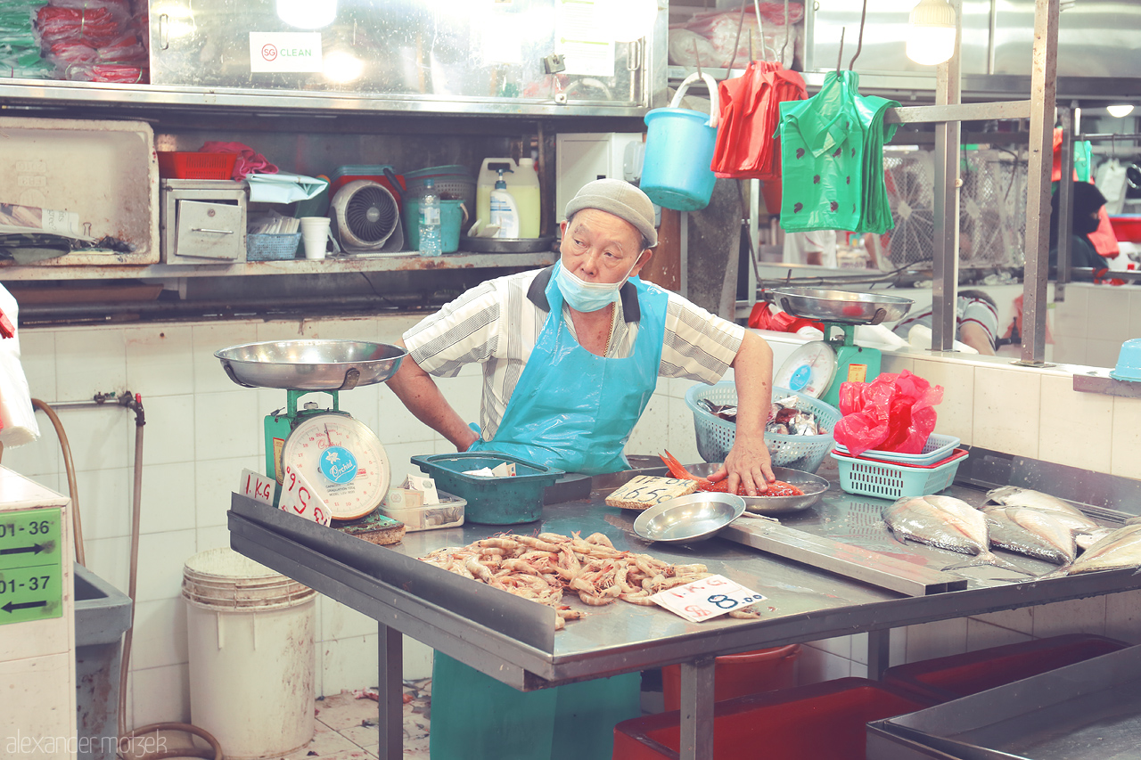 Foto von A local hawker meticulously arranging fresh seafood at a bustling market in Singapore, capturing the essence of traditional markets in the Lion City.