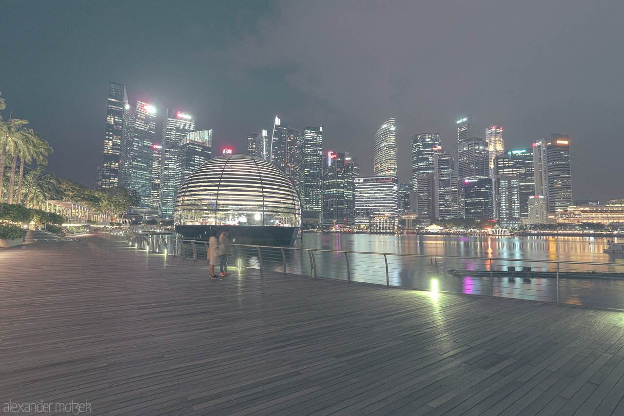 Foto von A serene evening at Marina Bay, Singapore, highlighted by the city skyline and a unique spherical structure against a twilight sky.