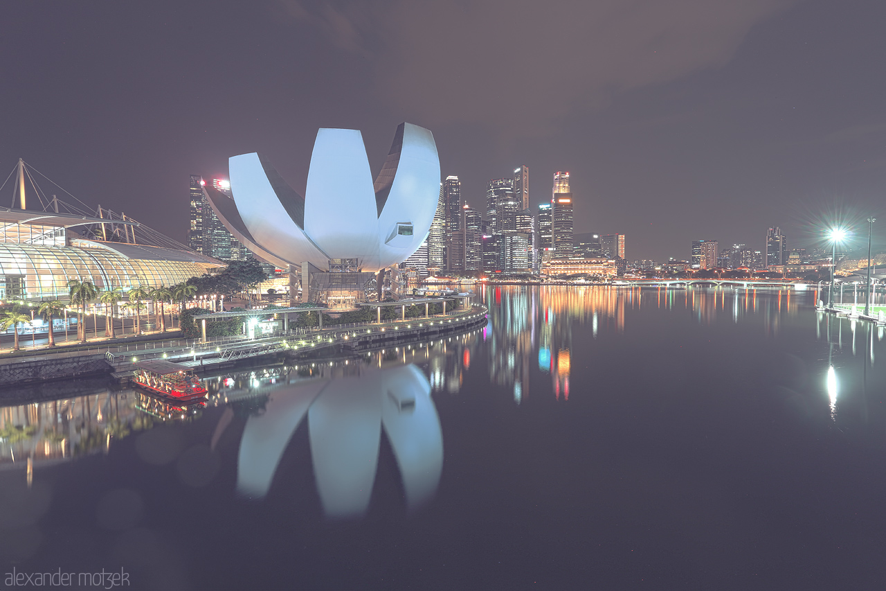 Foto von A serene night over Marina Bay, Singapore. The iconic ArtScience Museum and city skyline reflect beautifully on the tranquil waters, creating a mesmerizing scene.