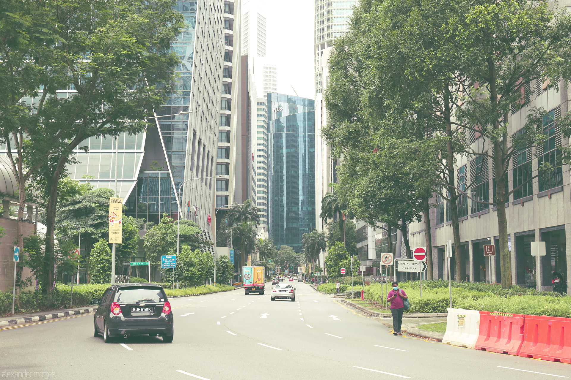 Lion City Jalan Dreaming Foto von A tree-lined street gently curves into Singapore’s CBD, where glass towers rise above tropical greenery in a tranquil cityscape blend.