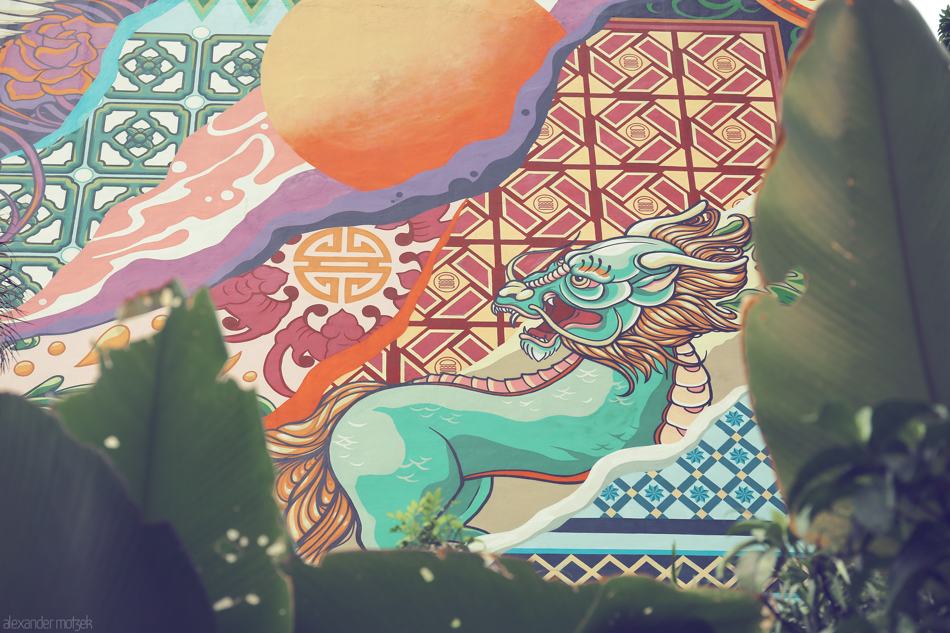 Draco Singapura Foto von A vibrant dragon mural peeks through tropical leaves, capturing Singapore's cultural fusion and street art energy.