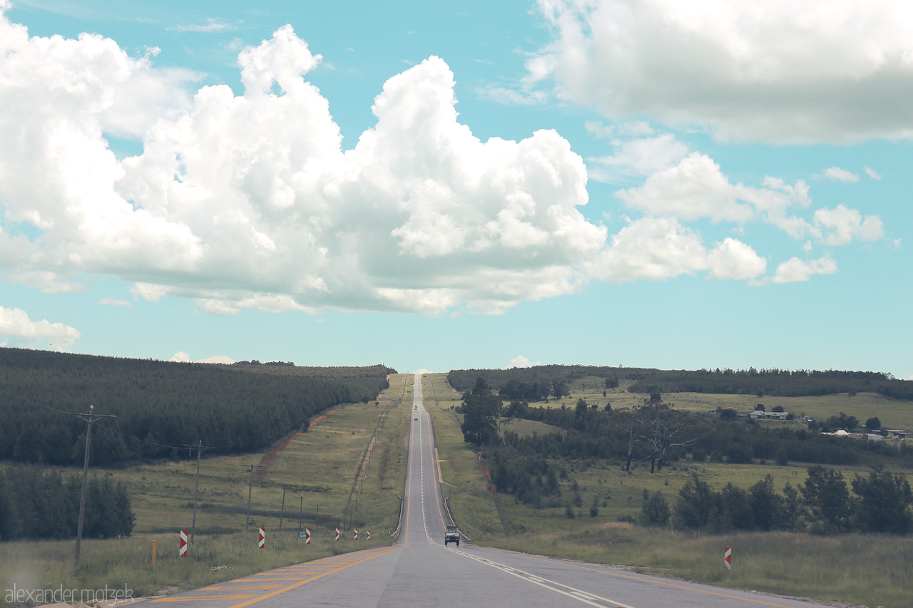 Foto von A long, open road stretches through Mpumalanga, South Africa, under a vast sky lined with fluffy clouds.