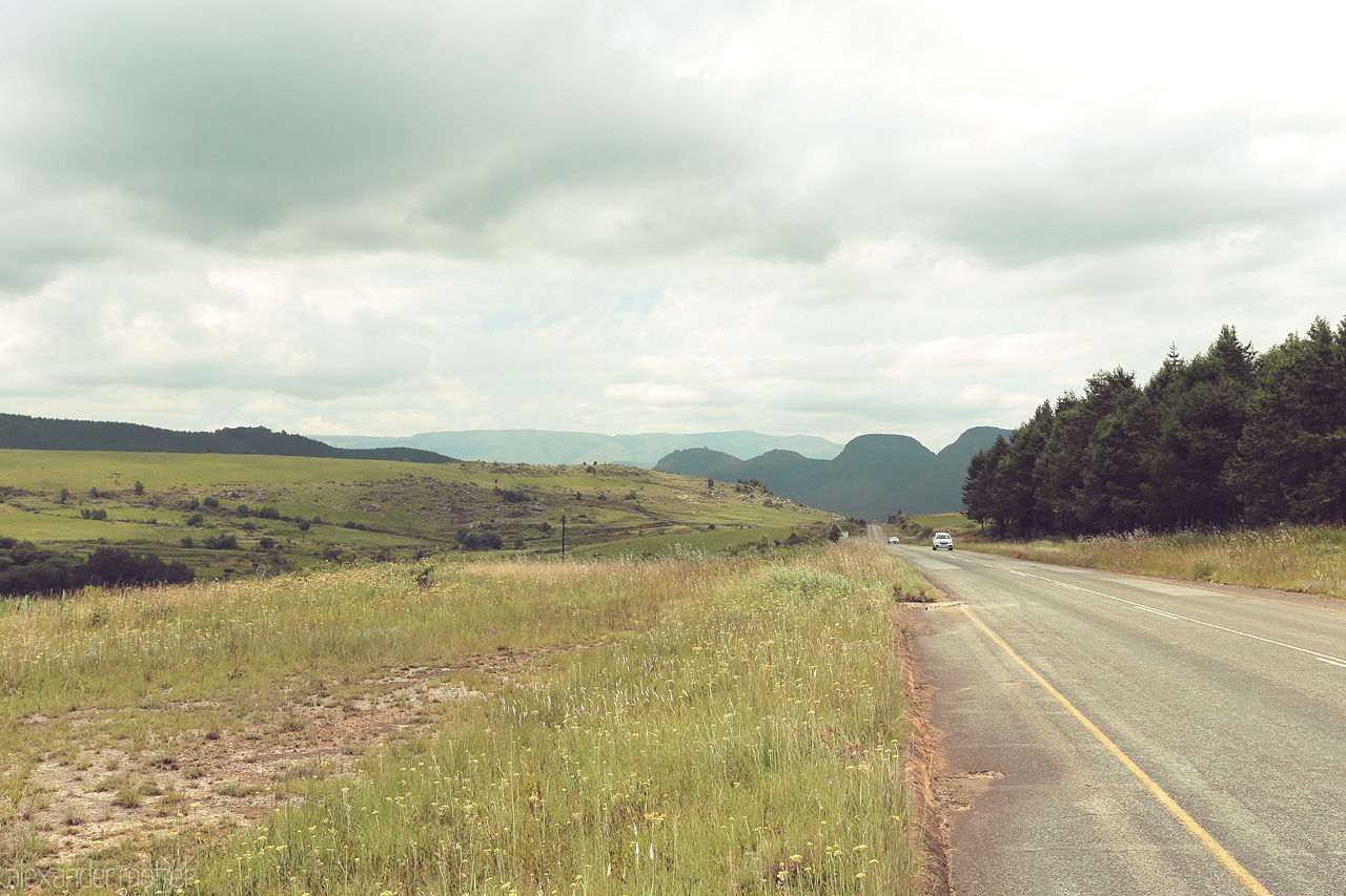 Foto von A serene road stretches through lush, rolling hills under a vast sky in Mpumalanga, South Africa.