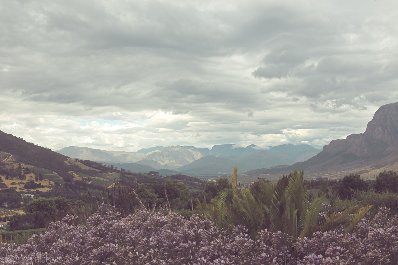 Foto von Dramatic skies over Stellenbosch's lush vineyards and rugged mountains, a serene view perfect for any traveler.