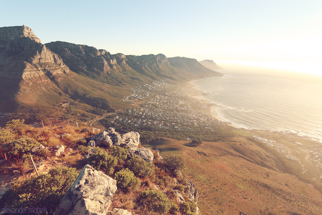 Foto von Golden hues over Cape Town's Lion's Head, capturing the vast ocean and rugged cliffs at sunset.