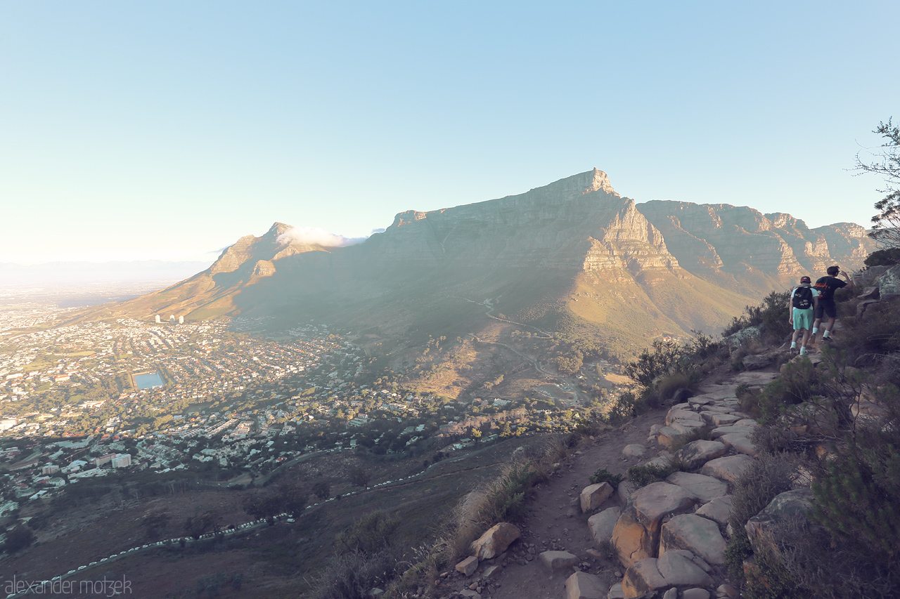 Foto von Hikers bask in the glow of sunrise on Lion's Head, Cape Town, overlooking the majestic Table Mountain.