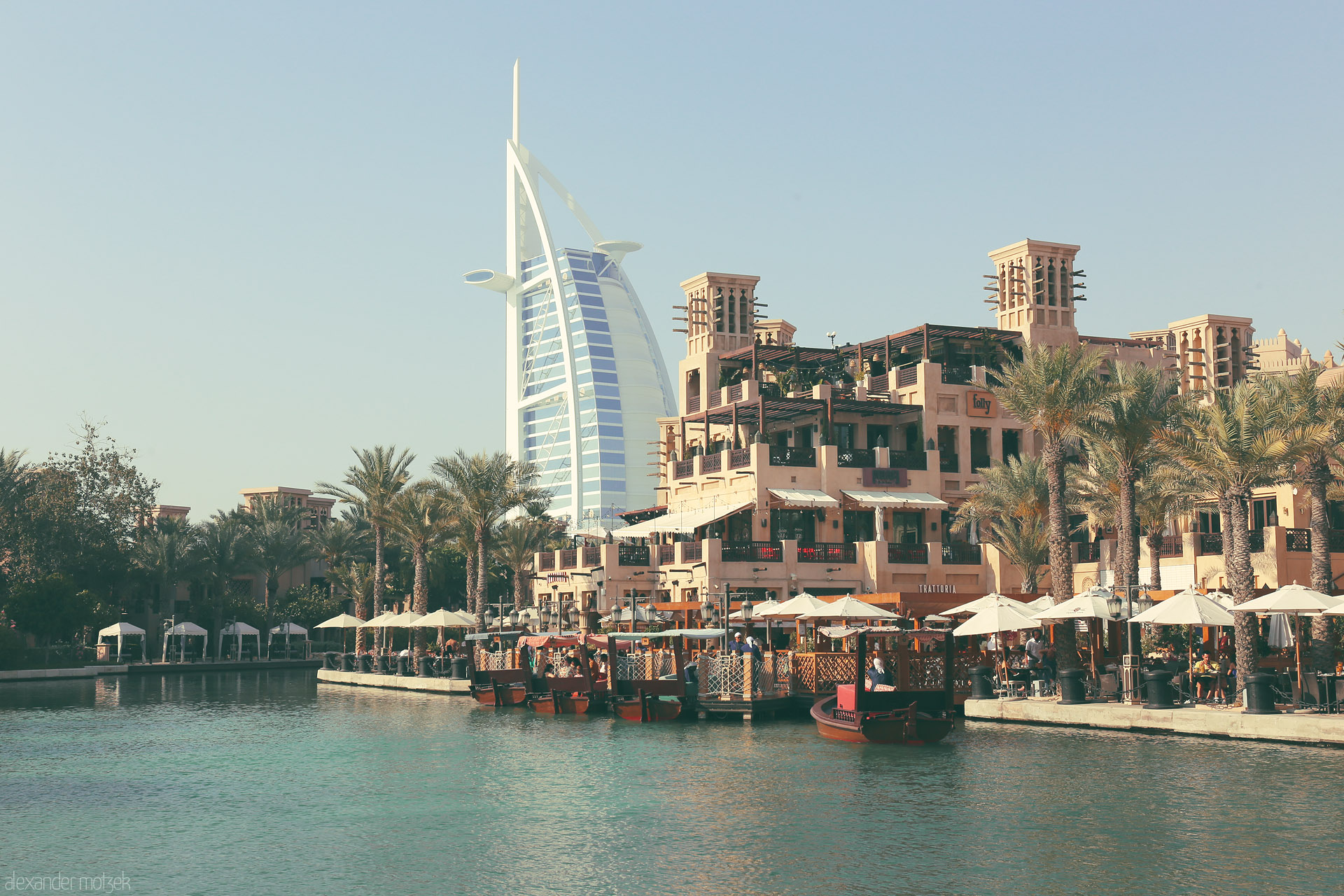 Foto von Traditional abra boats float by Madinat Jumeirah with Burj Al Arab gleaming in the Dubai sun.