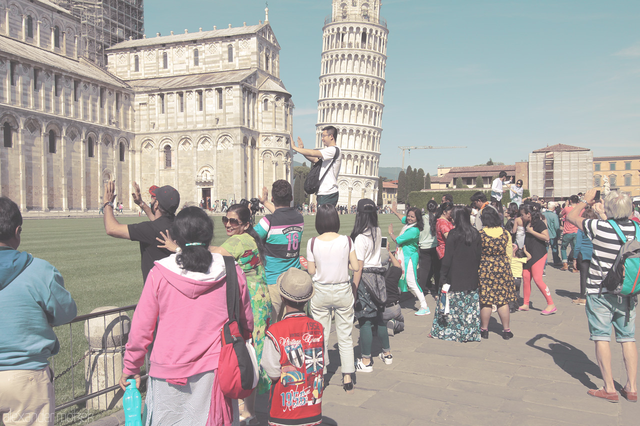 Foto von Tourists line up to capture their playful poses with the Leaning Tower in Pisa, Tuscany. Smiles and laughter fill the sunlit Italian square.