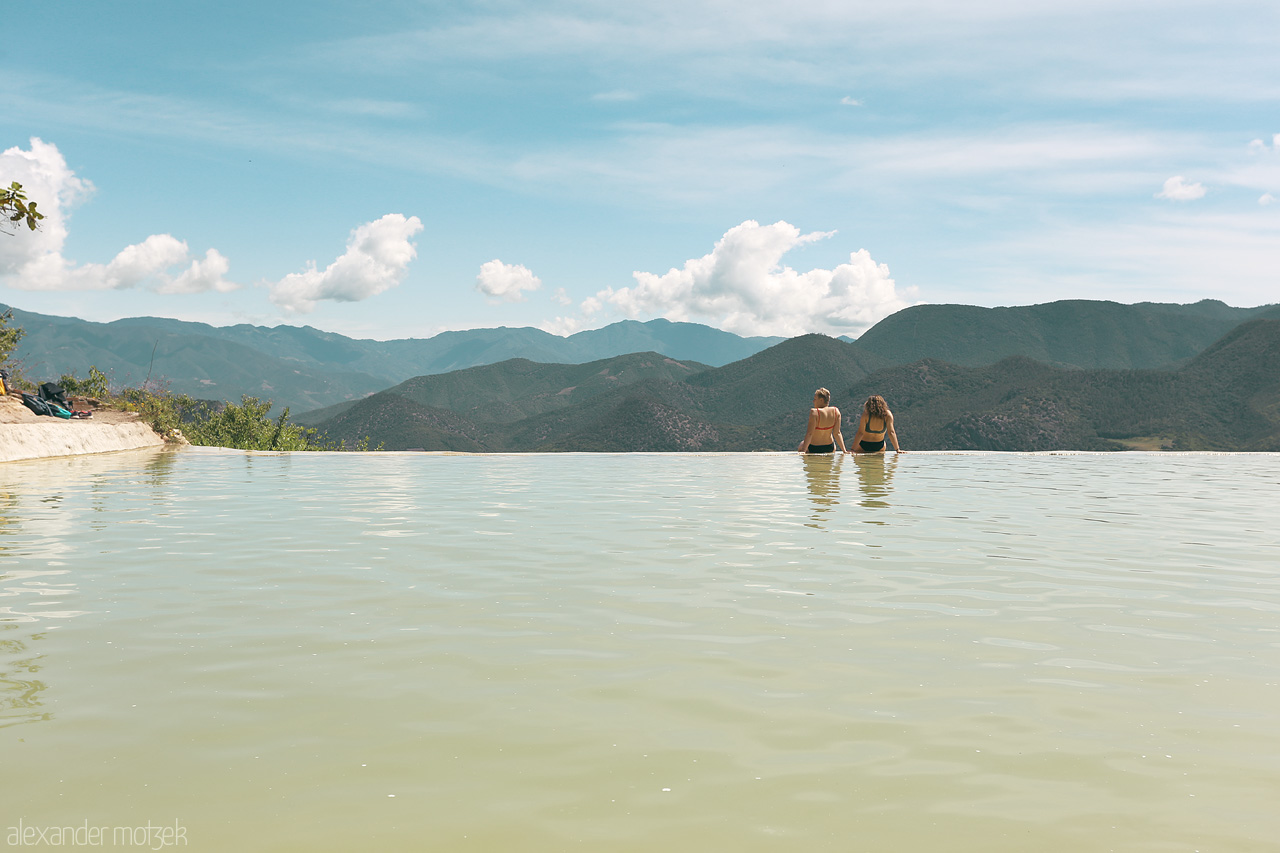 Hierve el Agua Foto von Two visitors wade in tranquil waters against a backdrop of Oaxaca's rolling hills.