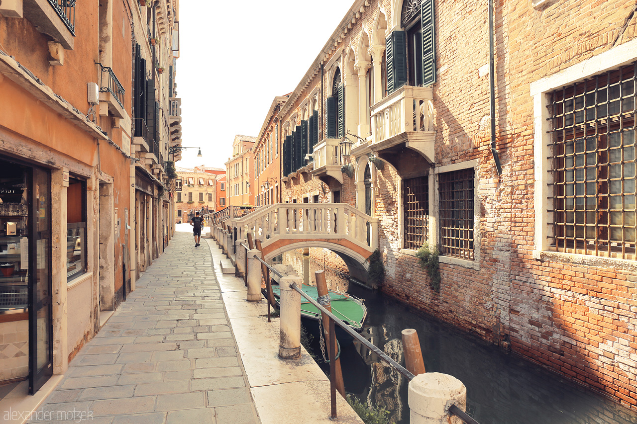Foto von A serene Venetian canal, flanked by ancient buildings with a quaint bridge under a warm glow.