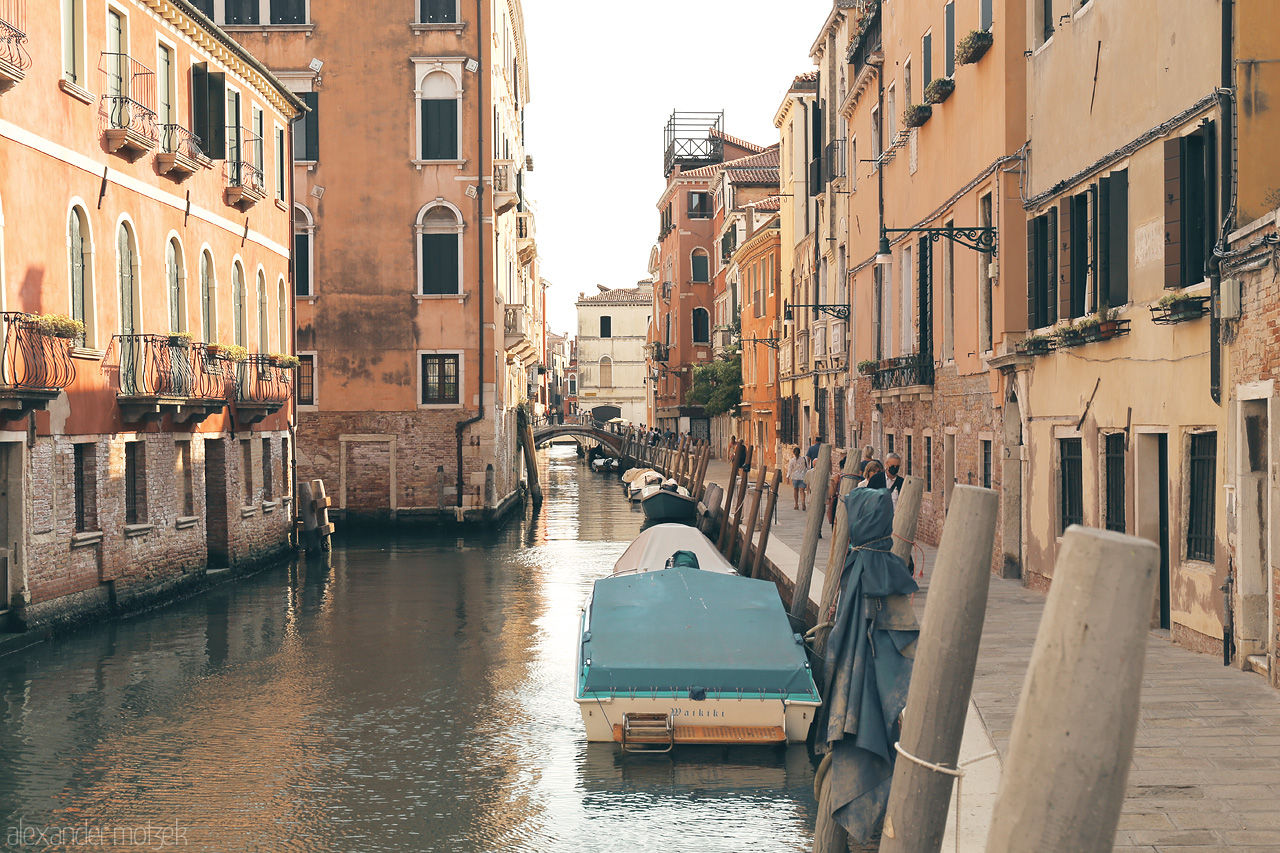 Foto von A serene canal lined with historic Venetian architecture, a bridge in the distance, under the soft glow of dusk.