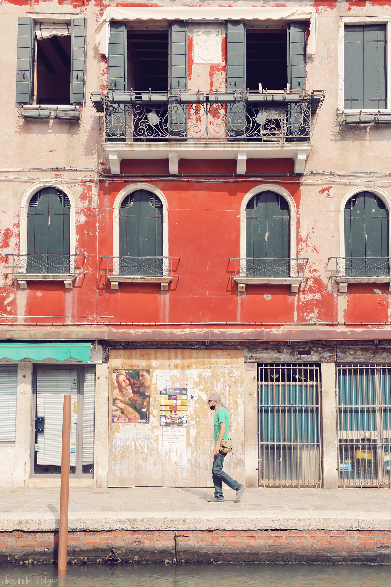 Foto von A solitary figure strides by a vibrant Venetian facade, reflecting the city's timeless allure.