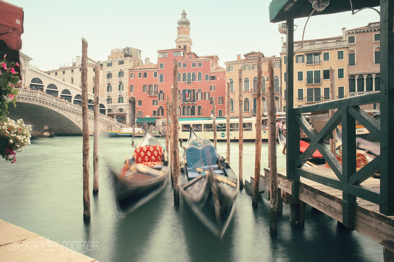 Foto von Blurred gondolas floating by a vibrant Venetian canal under an arching bridge; a still moment in dynamic Venice.