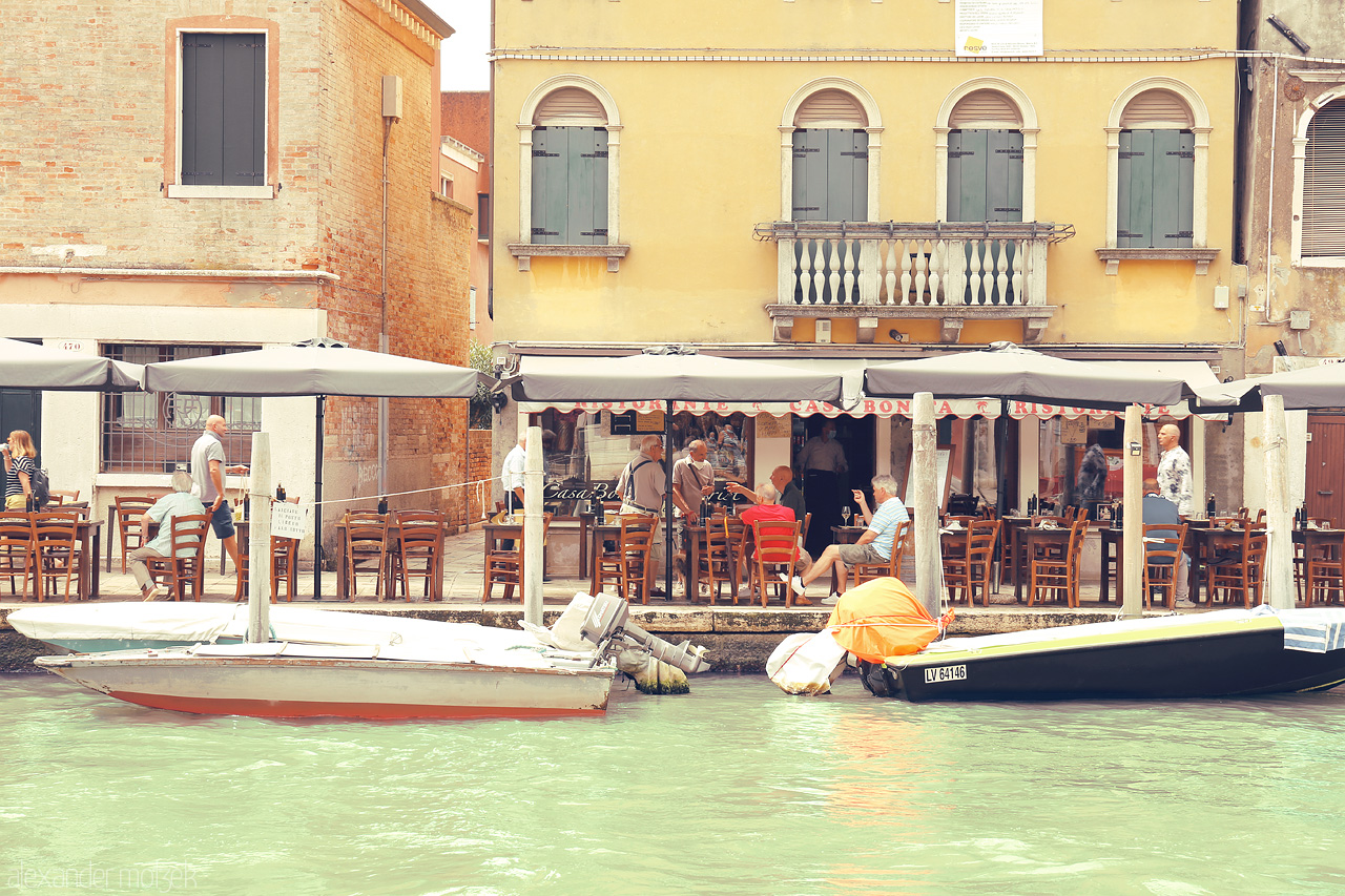 Foto von Quaint café life unfolds by Venice's serene canals, boats bobbing as patrons savor the city's charm.