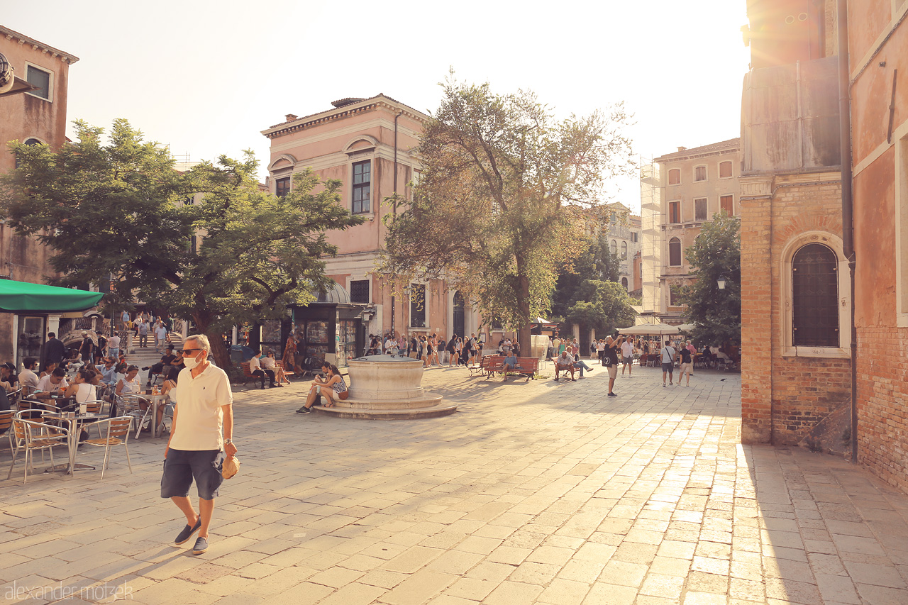 Foto von Warm sunlight bathes a bustling Venetian piazza, capturing the essence of daily life in the iconic city.