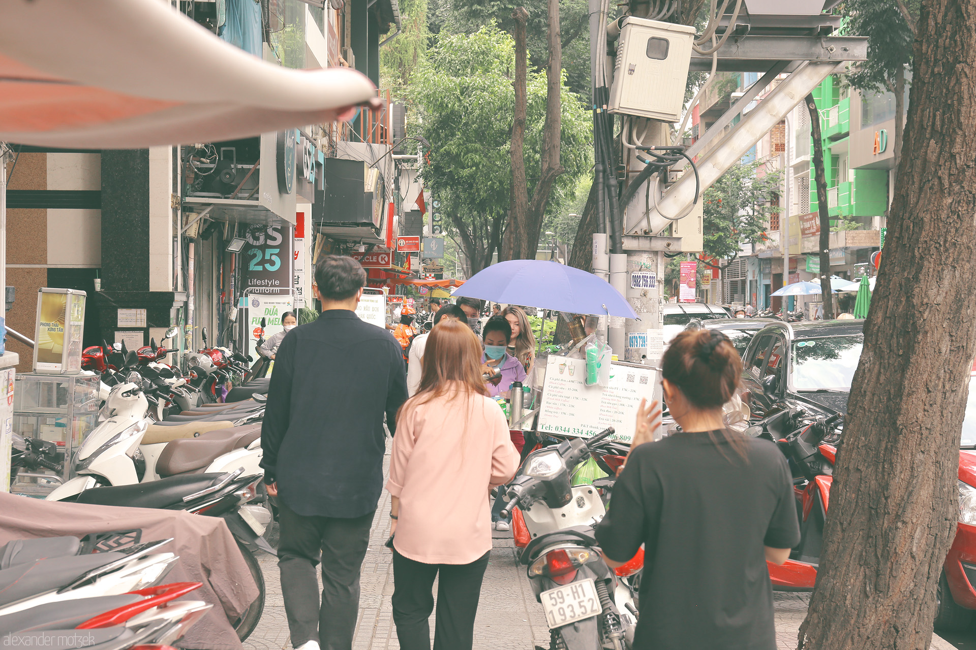 Saigon Sidewalk Symphony Foto von Bustling Saigon sidewalk: motorbikes, street vendors, and city life under umbrellas in Ho Chi Minh City, Vietnam.