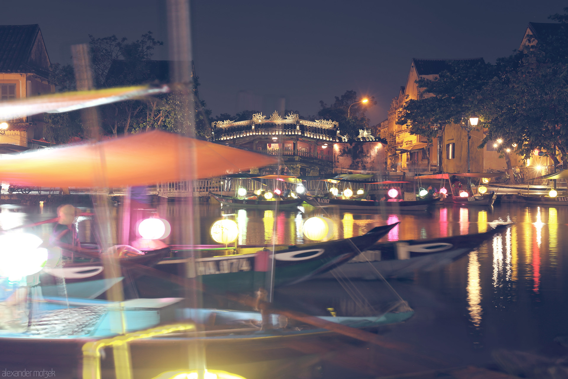 Moonlight on Thu Bon Foto von Glowing lanterns drift on Hoi An’s Thu Bon River, reflecting centuries-old charm under the ancient Chùa Cau bridge at night.