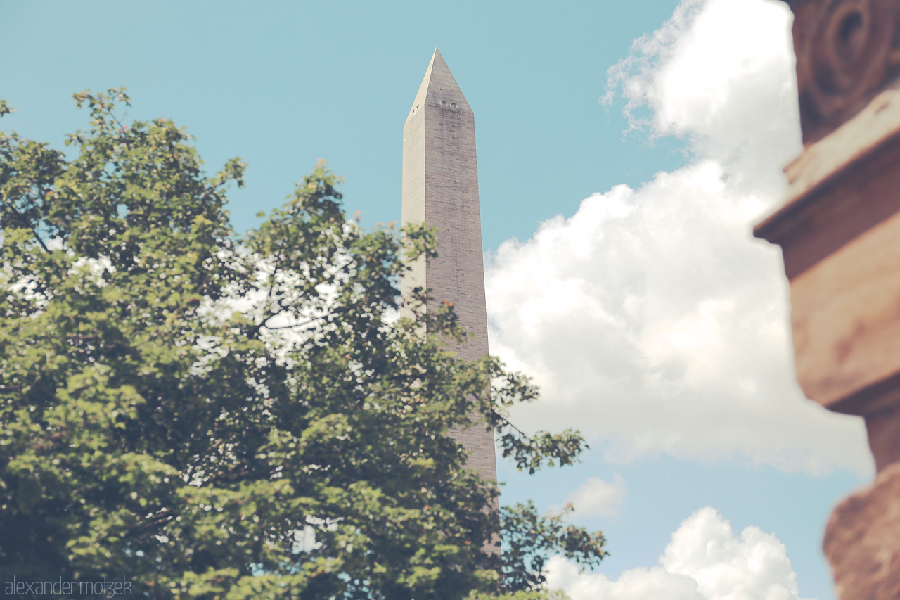 Foto von Capture the essence of DC with the Washington Monument standing tall against a backdrop of trees and clouds.