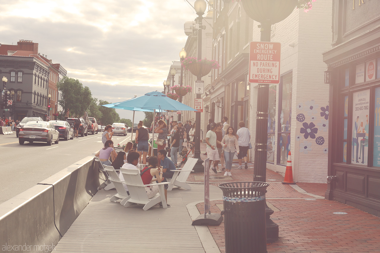 Foto von Relaxed summer vibes in Georgetown, D.C. capture locals lounging on a bustling street with vibrant shops and charming city atmosphere.