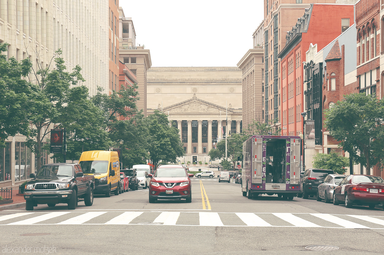 Foto von Street scene in Washington, D.C., capturing the blend of modern vehicles and historic architecture with a stately building in the background.